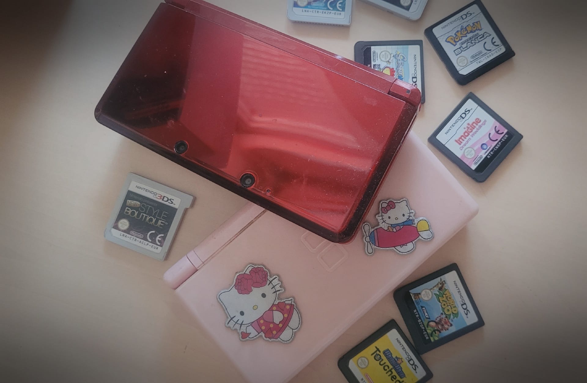 Consola Nintendo rosa y Nintendo 3DS roja junto con sus respectivos cartuchos de juegos.