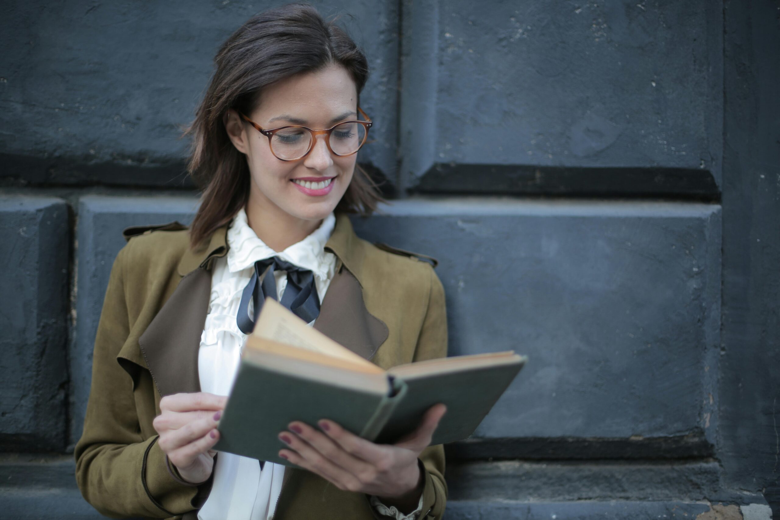 Chica con gafas leyendo un libro.